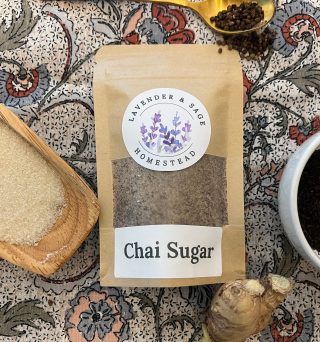 Package of Chai Sugar surrounded by black tea, ginger, cardamom, and sugar